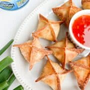 Overhead shot of cream cheese tuna wontons on a place served with a red sauce.