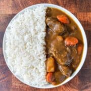 Japanese beef curry served in a white plate with rice on the side.