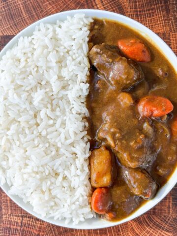Japanese beef curry served in a white plate with rice on the side.