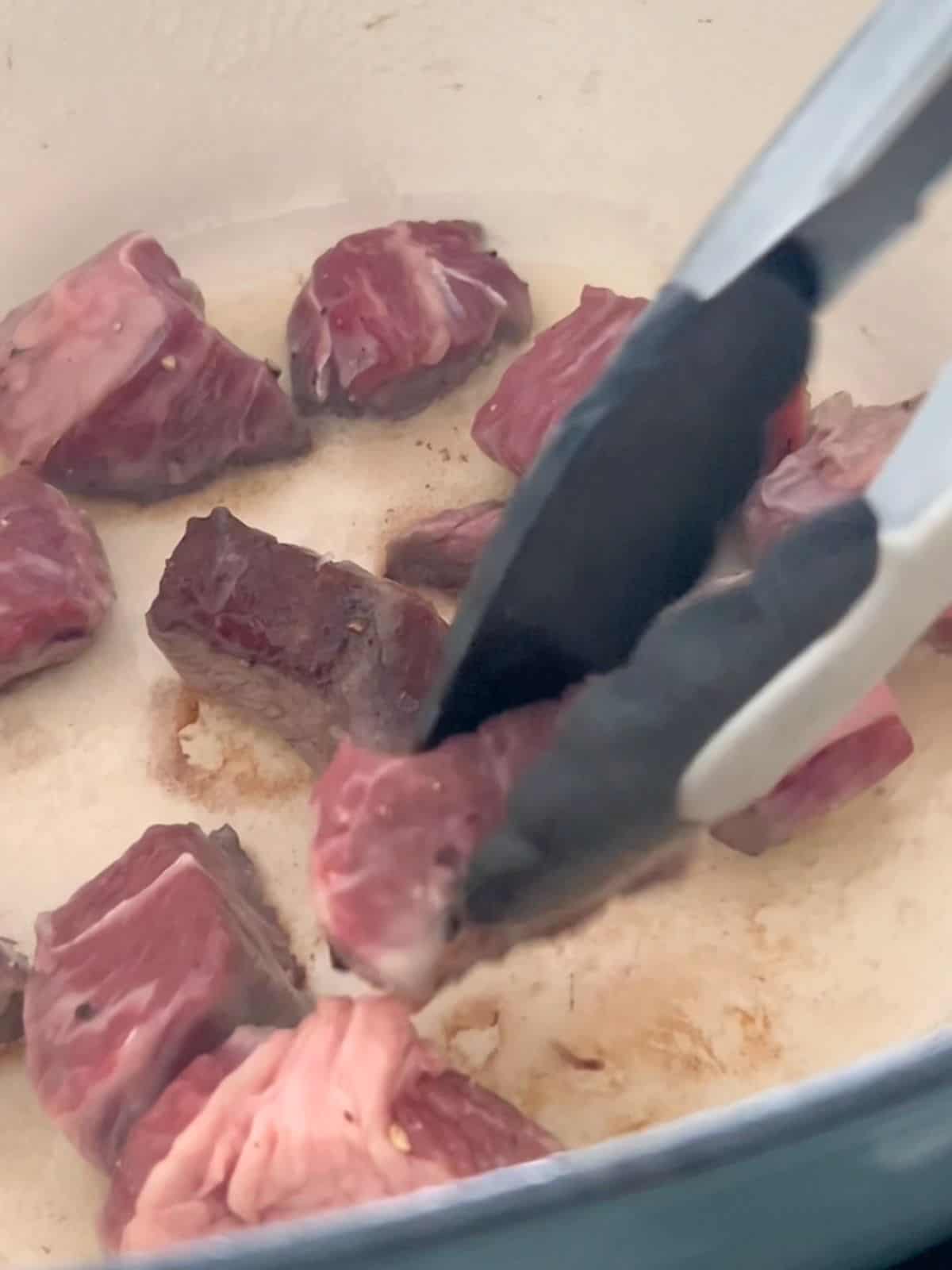 Searing the beef in a Dutch oven.