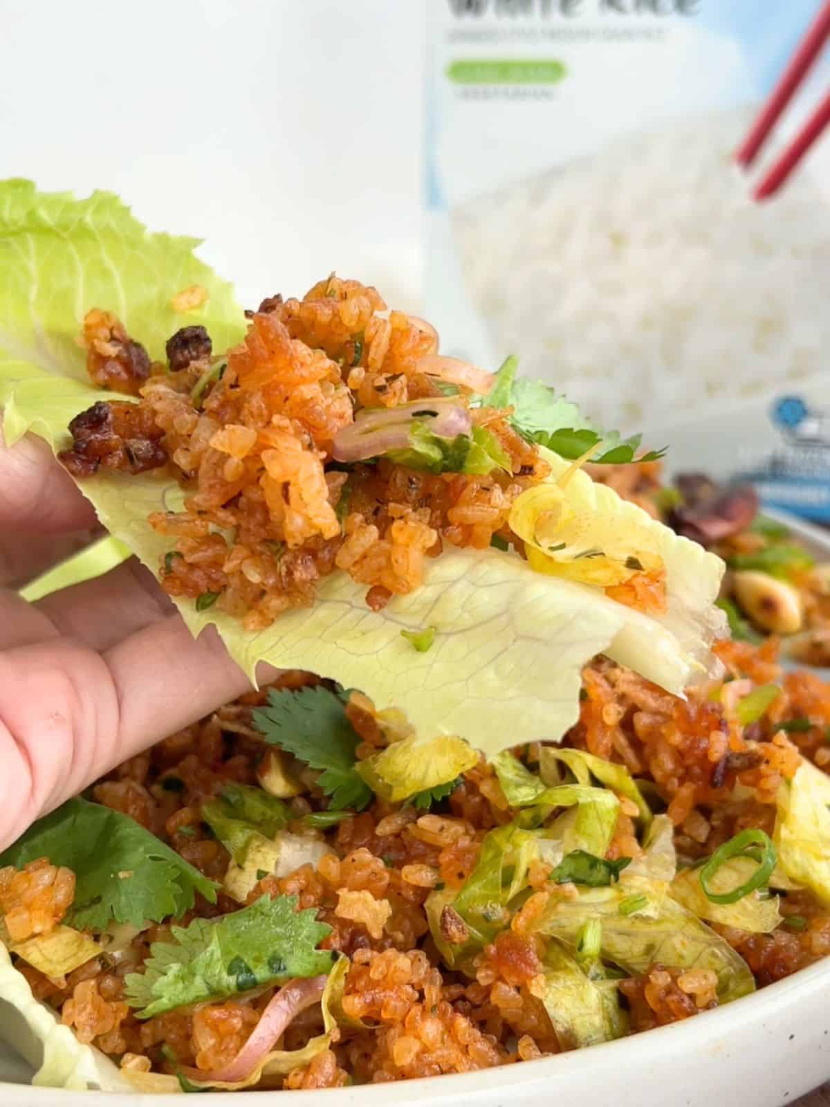 Hand holding a piece of lettuce with a scoop of the crispy rice salad on top.