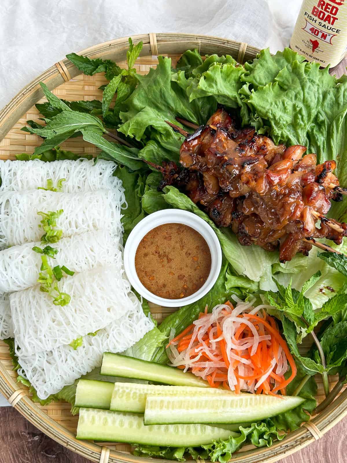 Overhead shot of hot honey skewers served with rice noodles, veggies and fish sauce glaze.