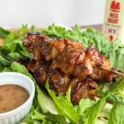 Hot honey glazed chicken skewers on a bed of lettuce.