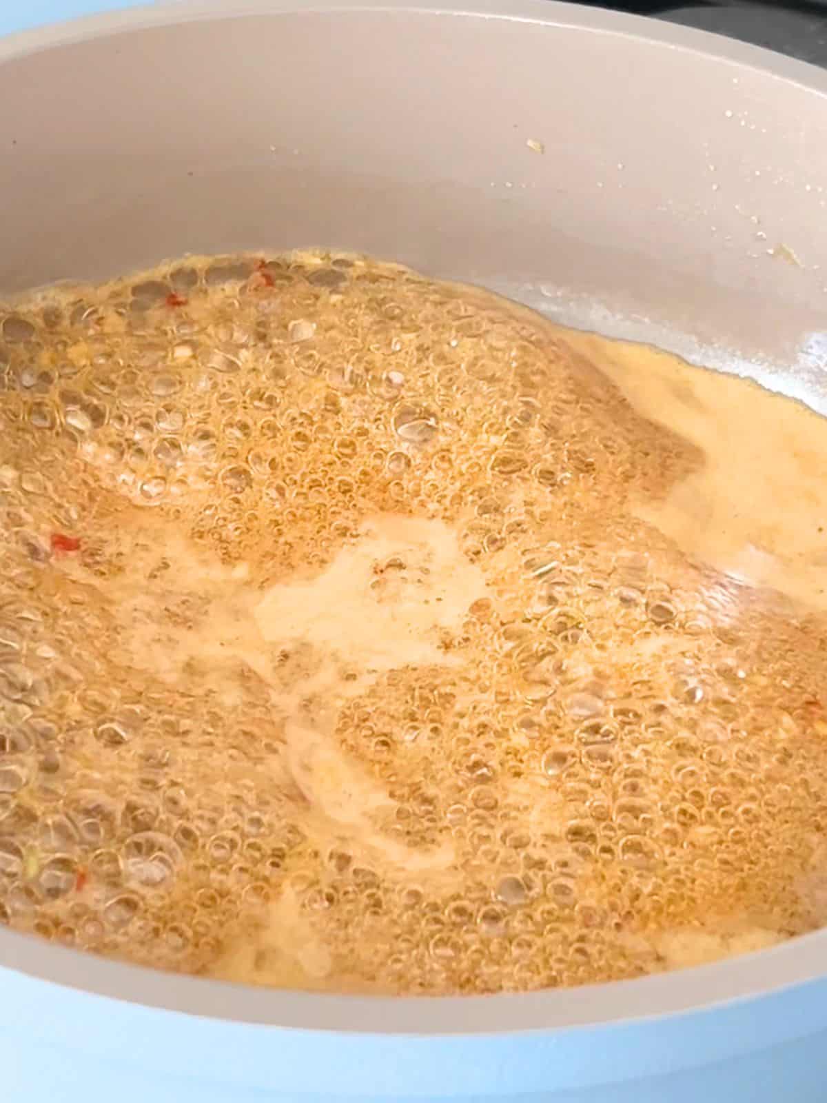 Fish sauce hot honey glaze being cooked in a skillet.