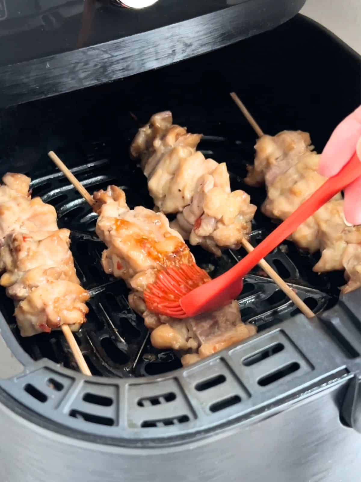 Brushing the chicken skewers with glaze while in the air fryer.