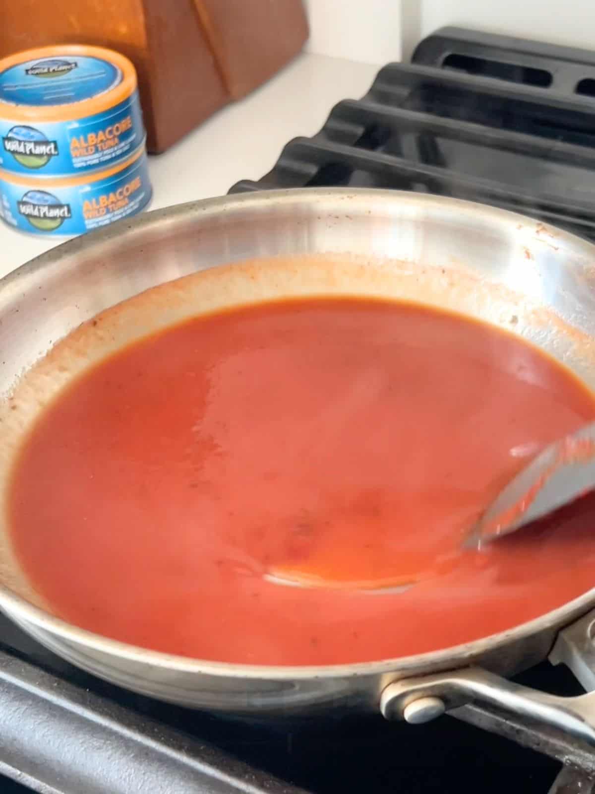 Making the homemade BBQ sauce in a skillet before it has thickened.
