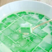 Pandan custard cut up into squares and topped with coconut milk.