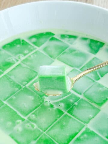 Pandan custard cut up into squares and topped with coconut milk.