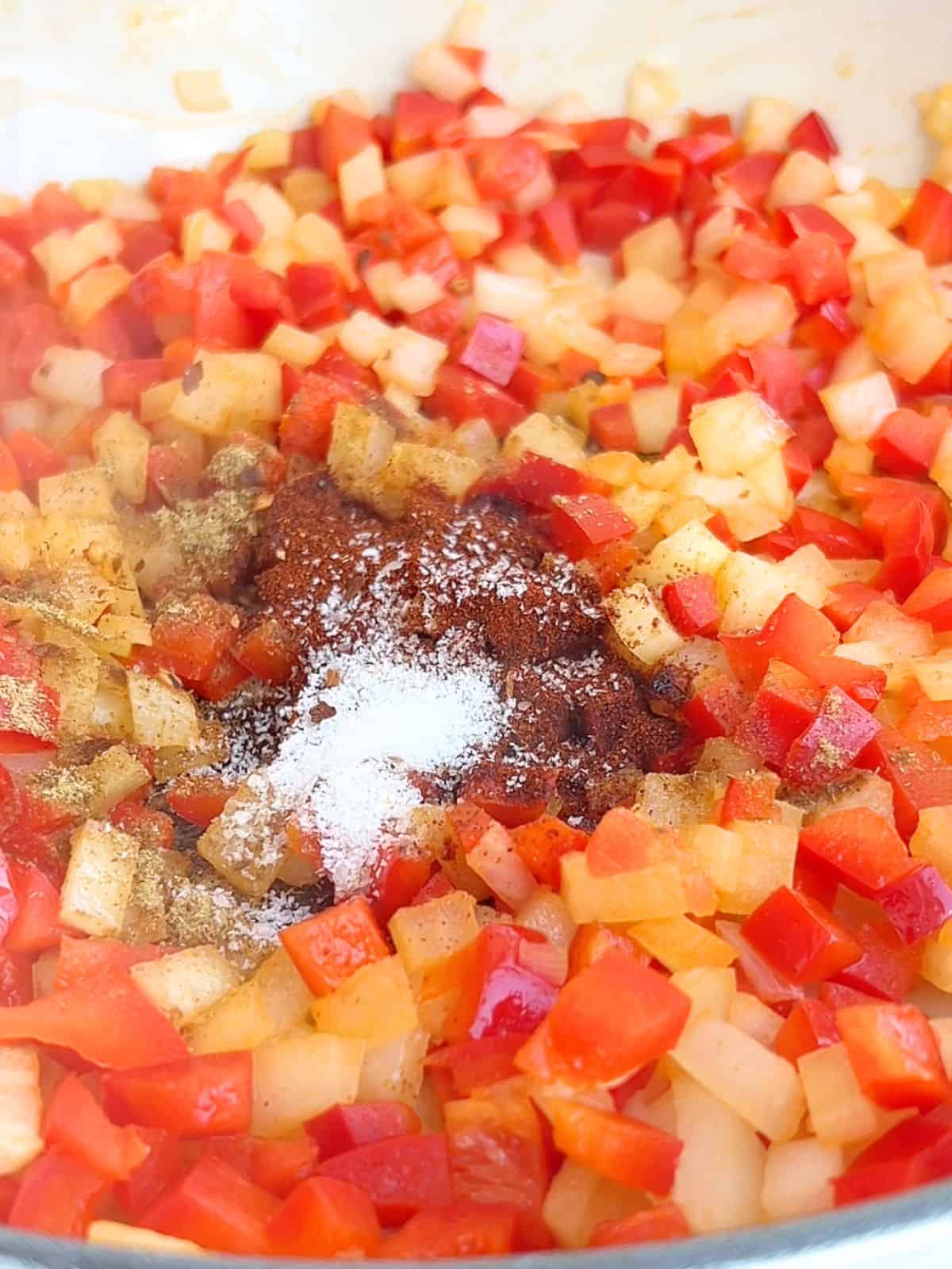 Diced onions and peppers with spices in a skillet.