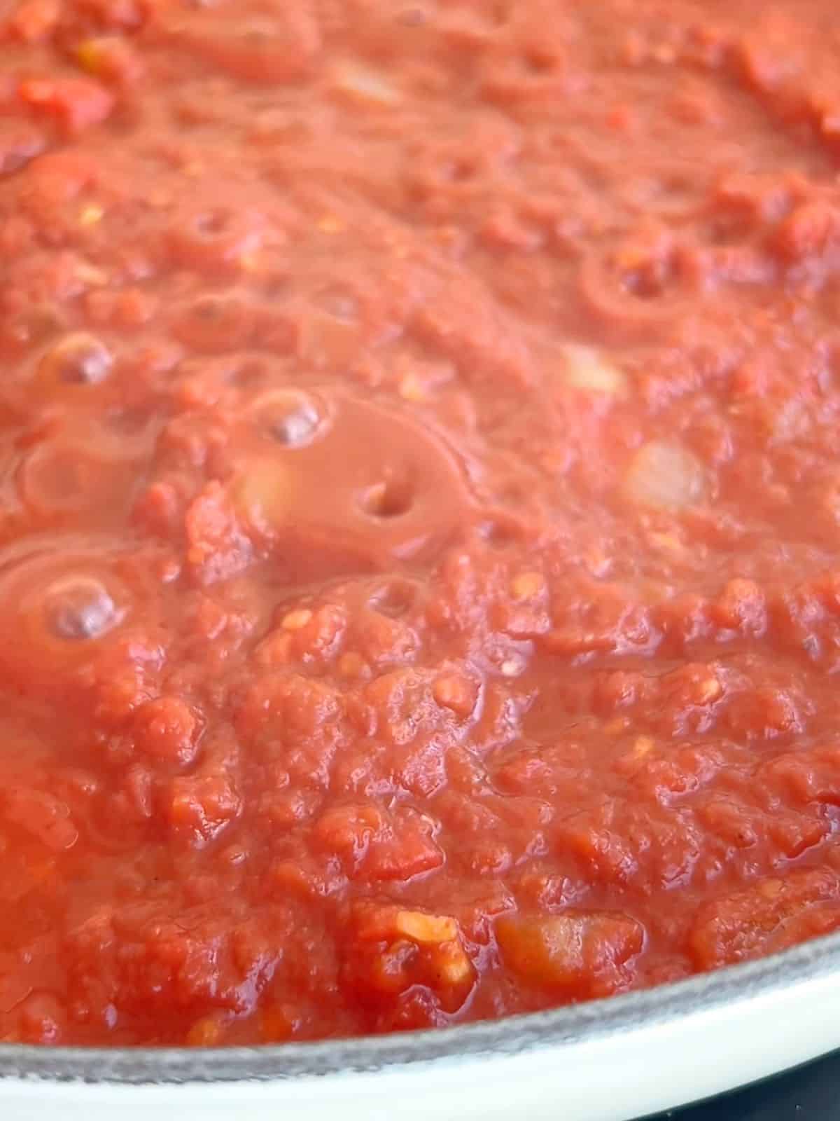 Tomato and pepper mixture simmering in a skillet.
