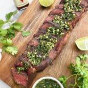 Sliced steak with jeow som on a wooden board.