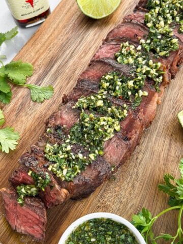 Sliced steak with jeow som on a wooden board.