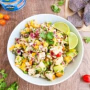 Mango tuna ceviche served in a white bowl with a side of lime wedges.