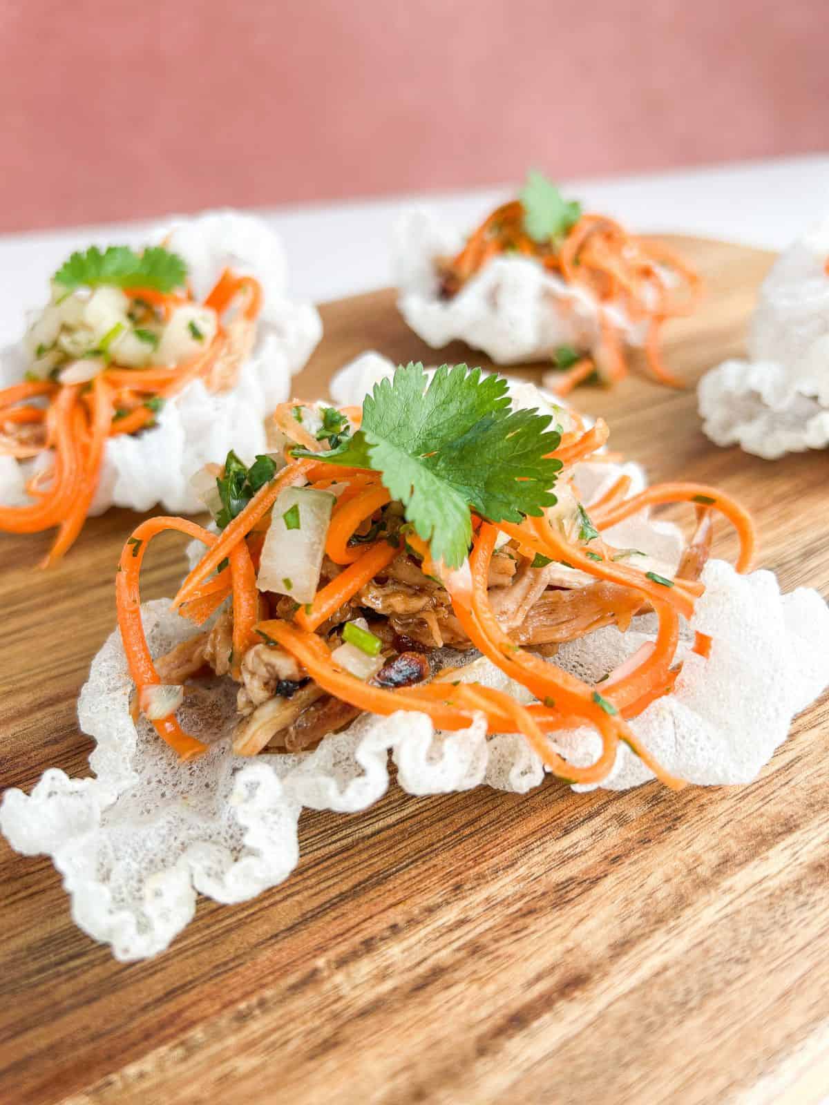 Finished Vietnamese chicken tostadas served on a wooden board.
