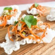 Crispy Vietnamese chicken tostada on a wooden board topped with cilantro.