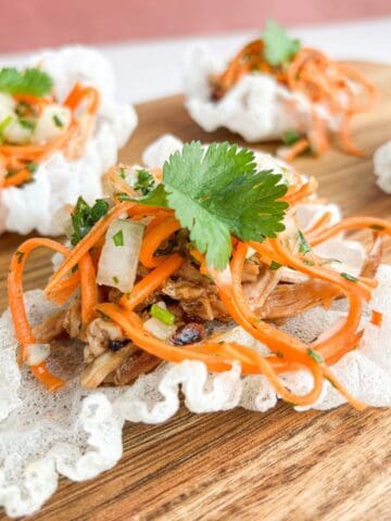Crispy Vietnamese chicken tostada on a wooden board topped with cilantro.