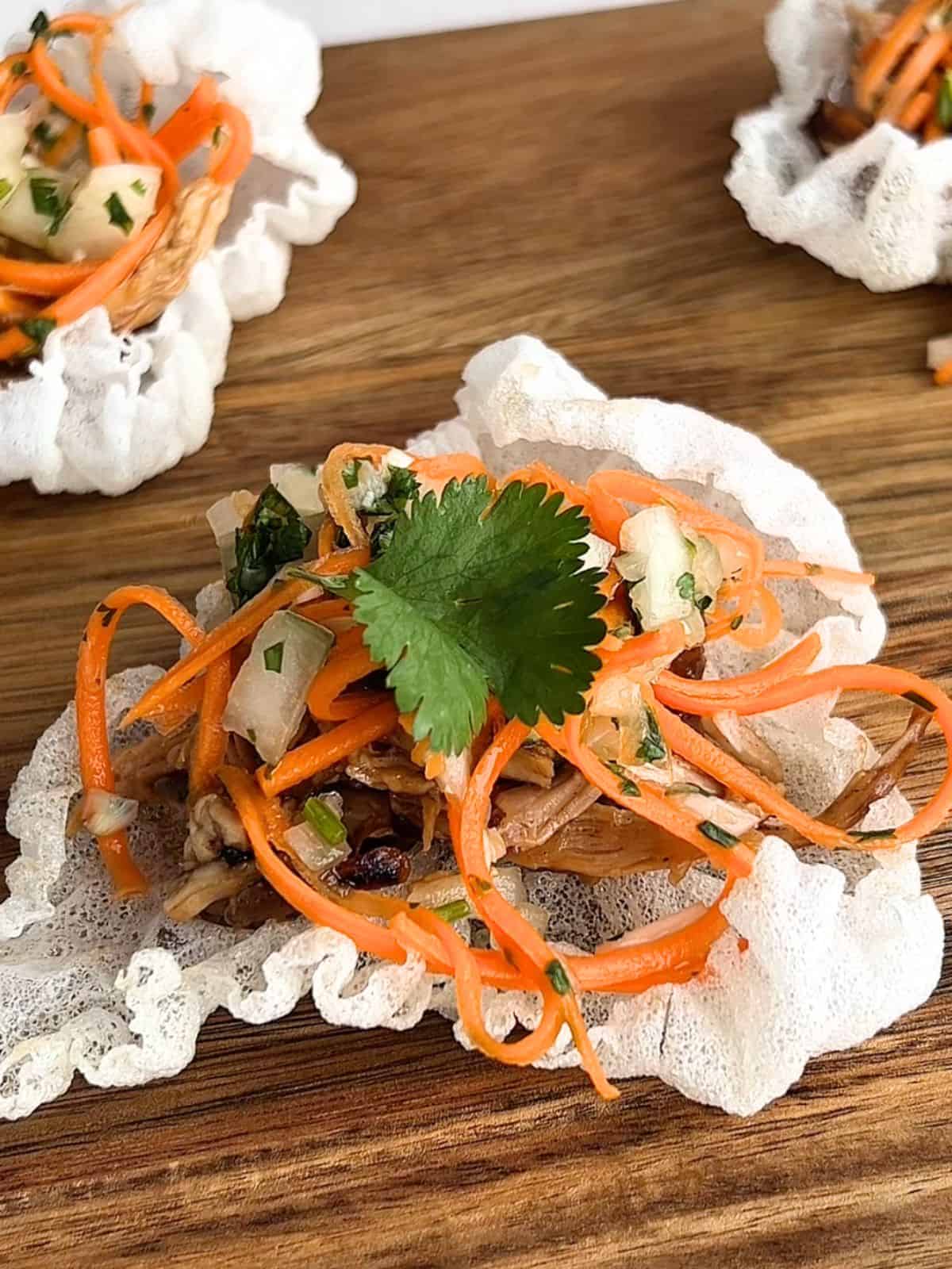 Assembling the Vietnamese chicken tostadas with crispy rice paper, shredded chicken, and pico de gallo.