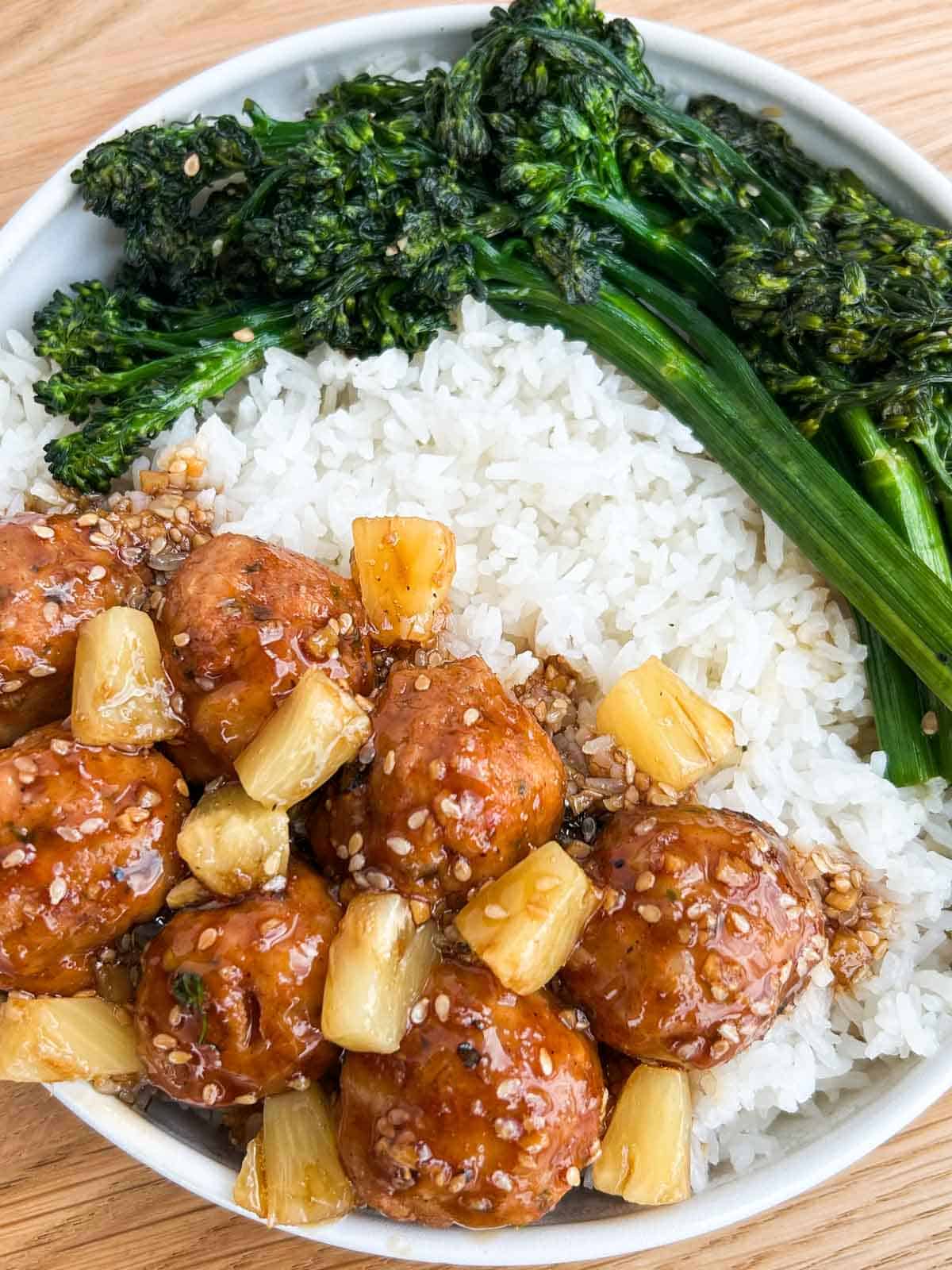 Top down shot of the chicken meatballs on top of rice with broccolini.
