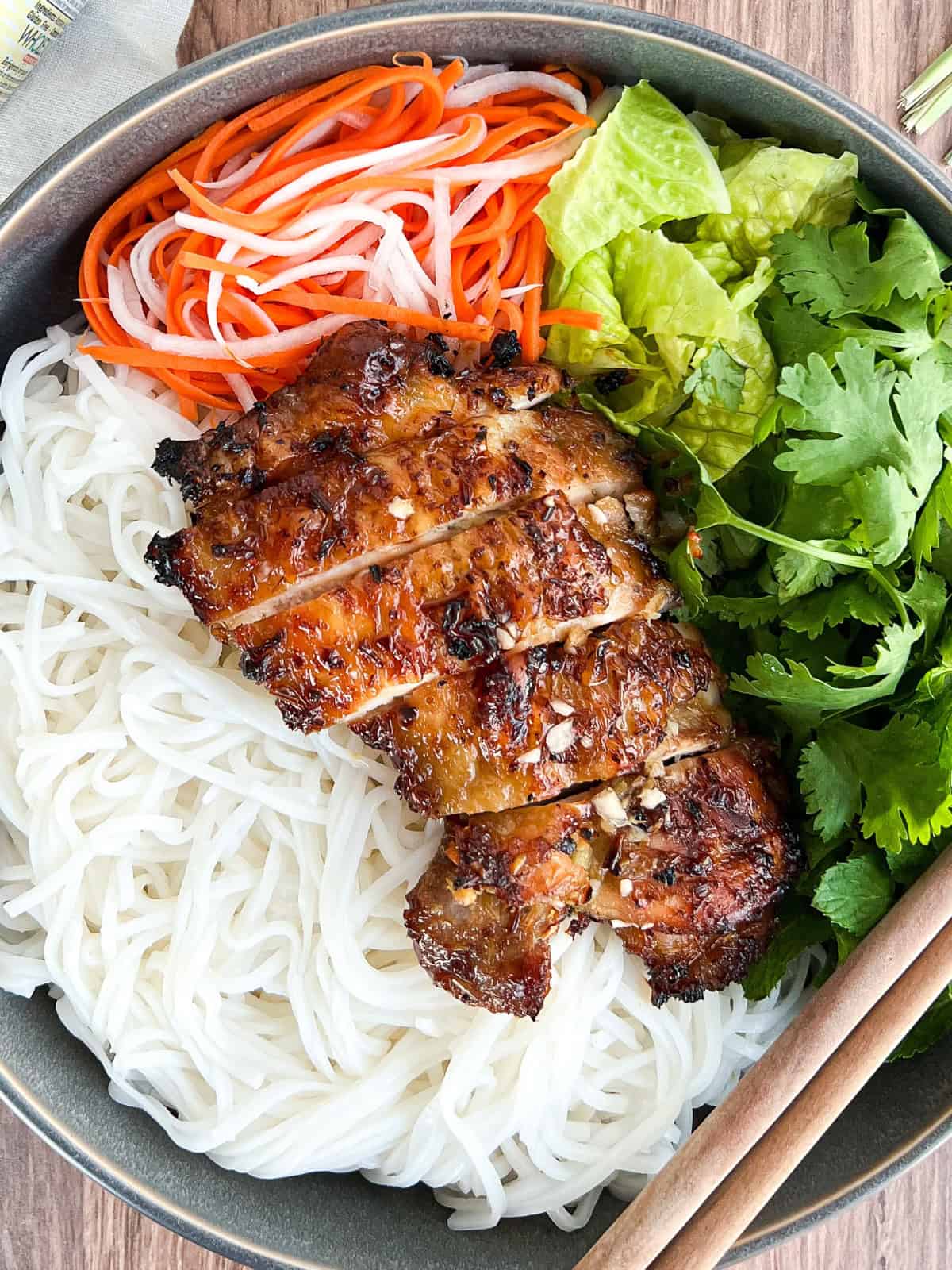 Sliced air fryer lemongrass chicken on a bed of noodles and veggies.