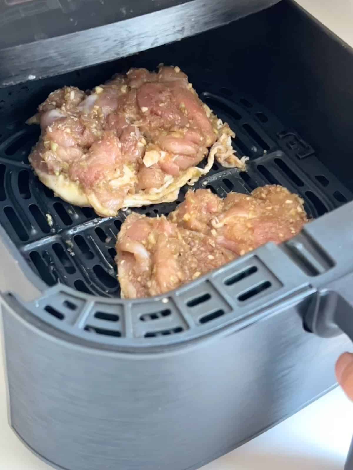Chicken thighs skin side down in the air fryer basket.