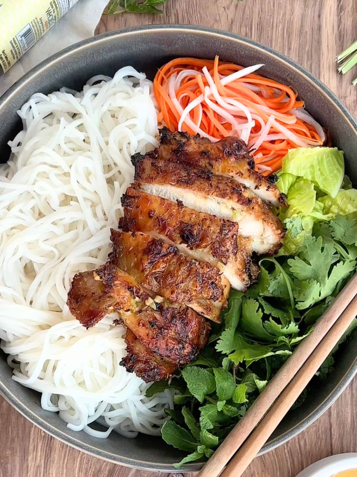 Sliced lemongrass chicken thigh served with noodles and veggies.