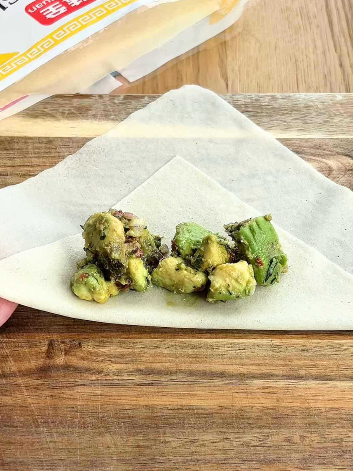 Adding avocado filling to the egg roll wrapper.