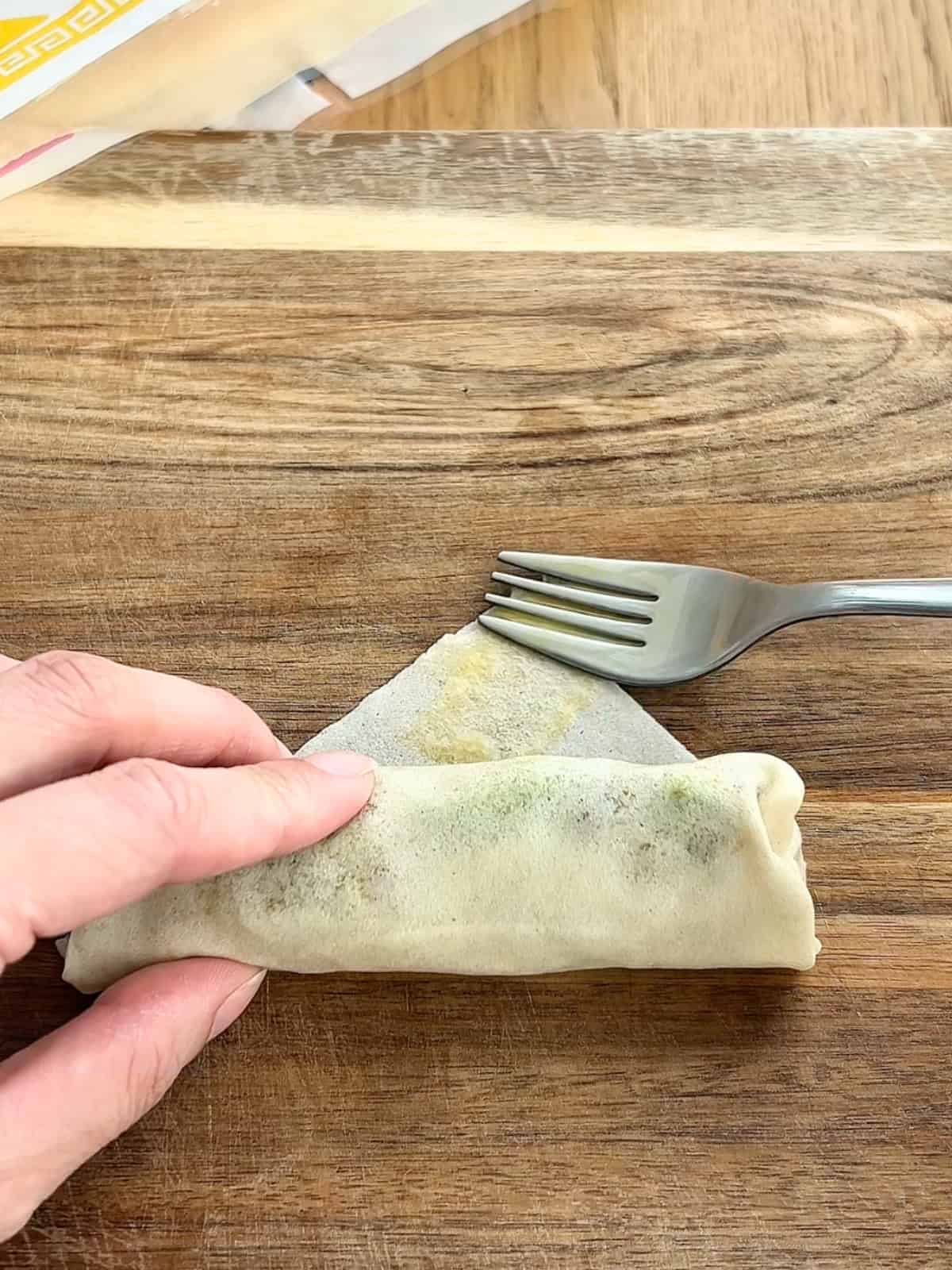 Using an egg wash to seal the egg roll.