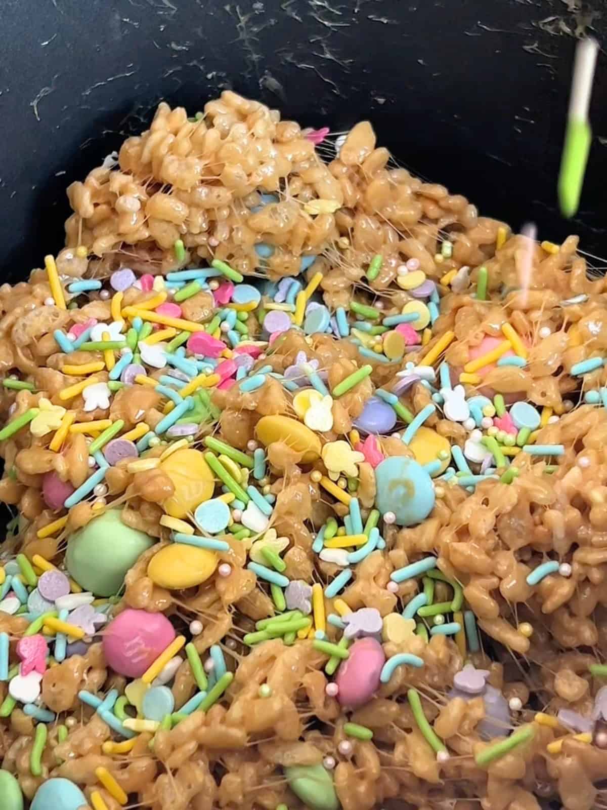 Adding candies and sprinkles to the rice krispy mixture.