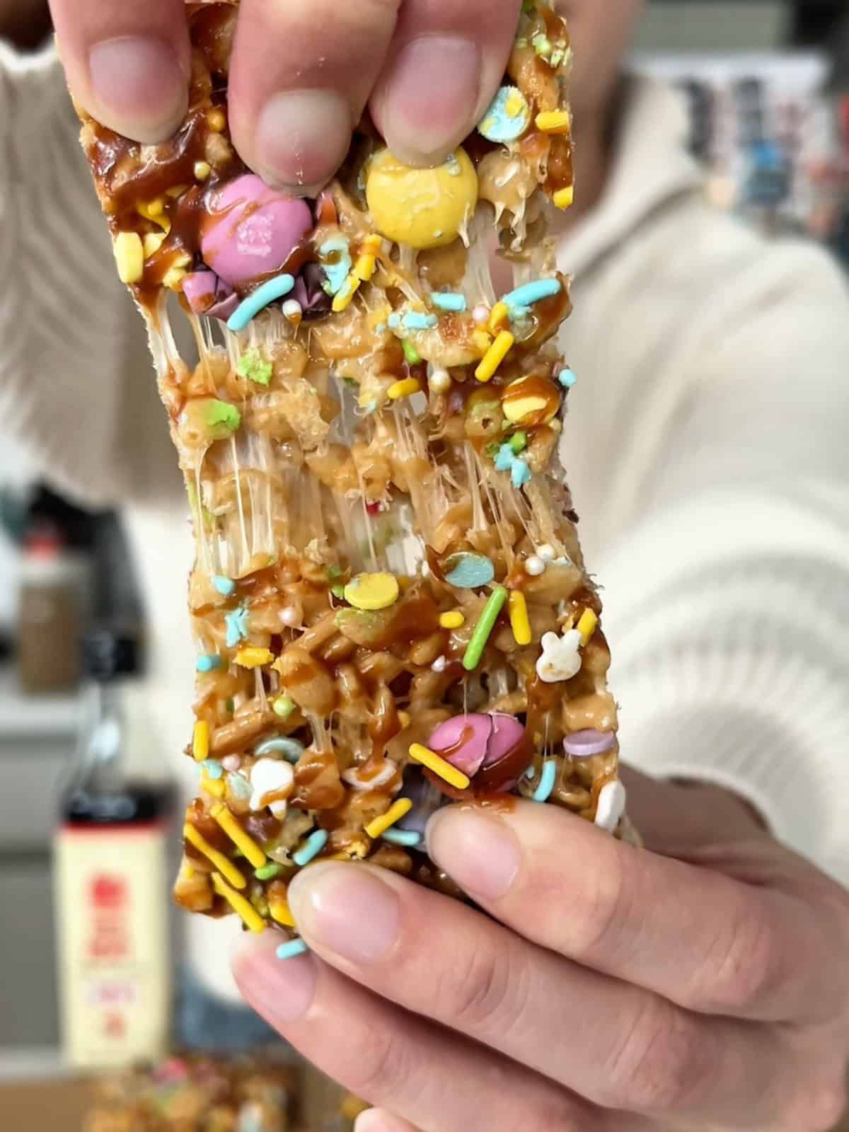 Two hands pulling a fish sauce rice krispy treat apart.
