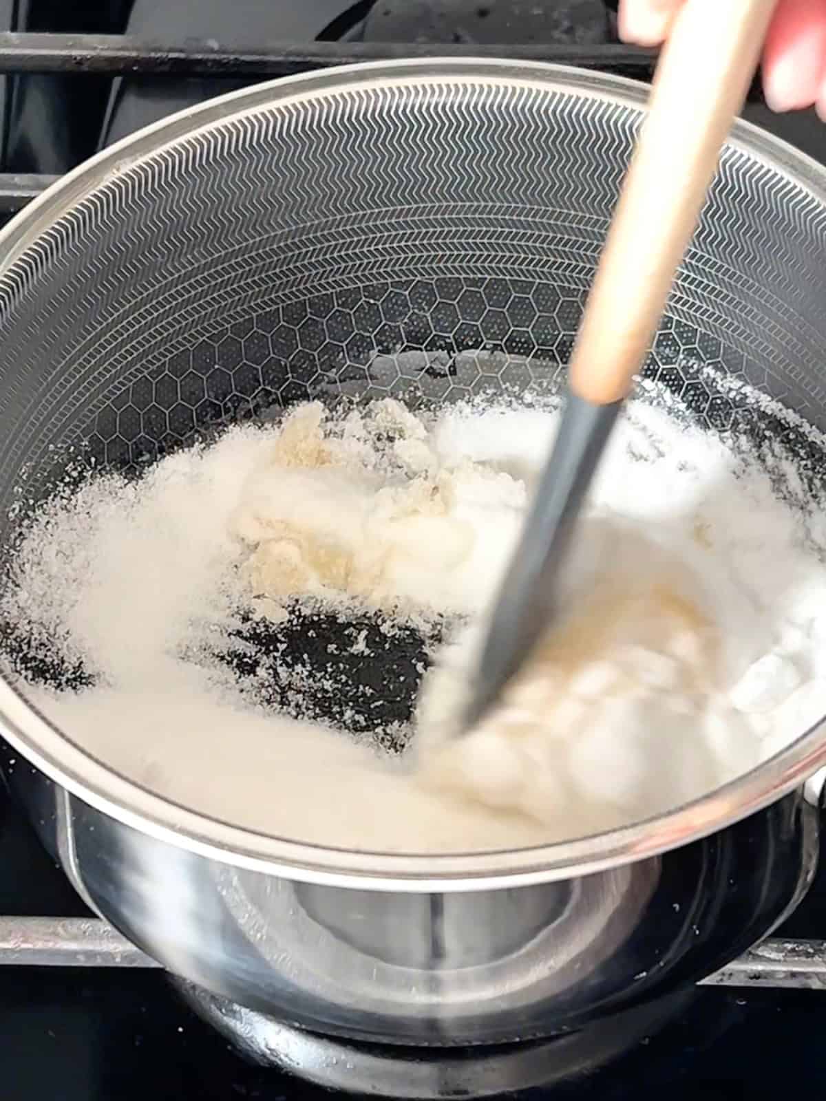 Making the caramel by stirring sugar in a pan.