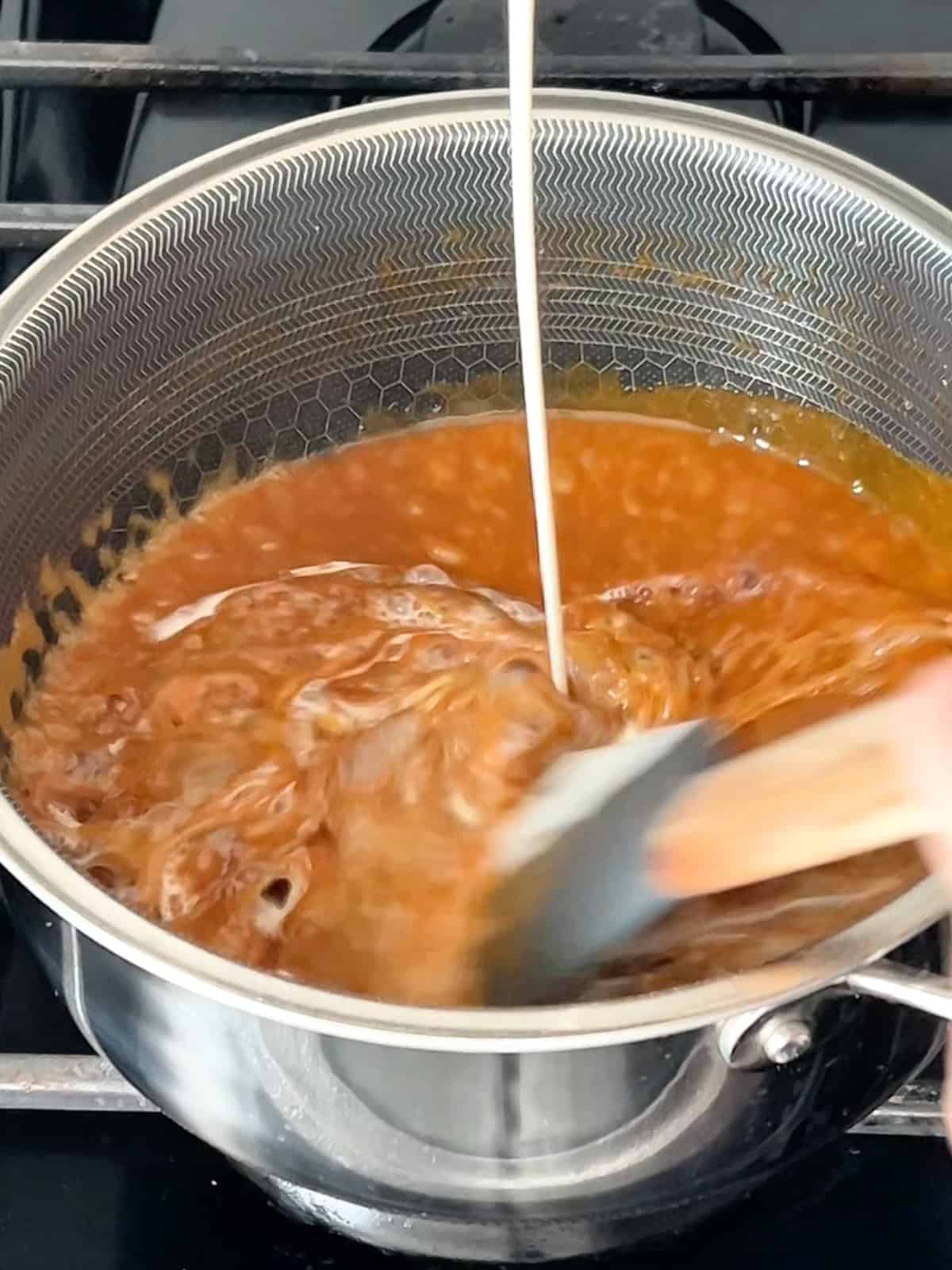 Pouring in the heavy cream into the cooking caramel.