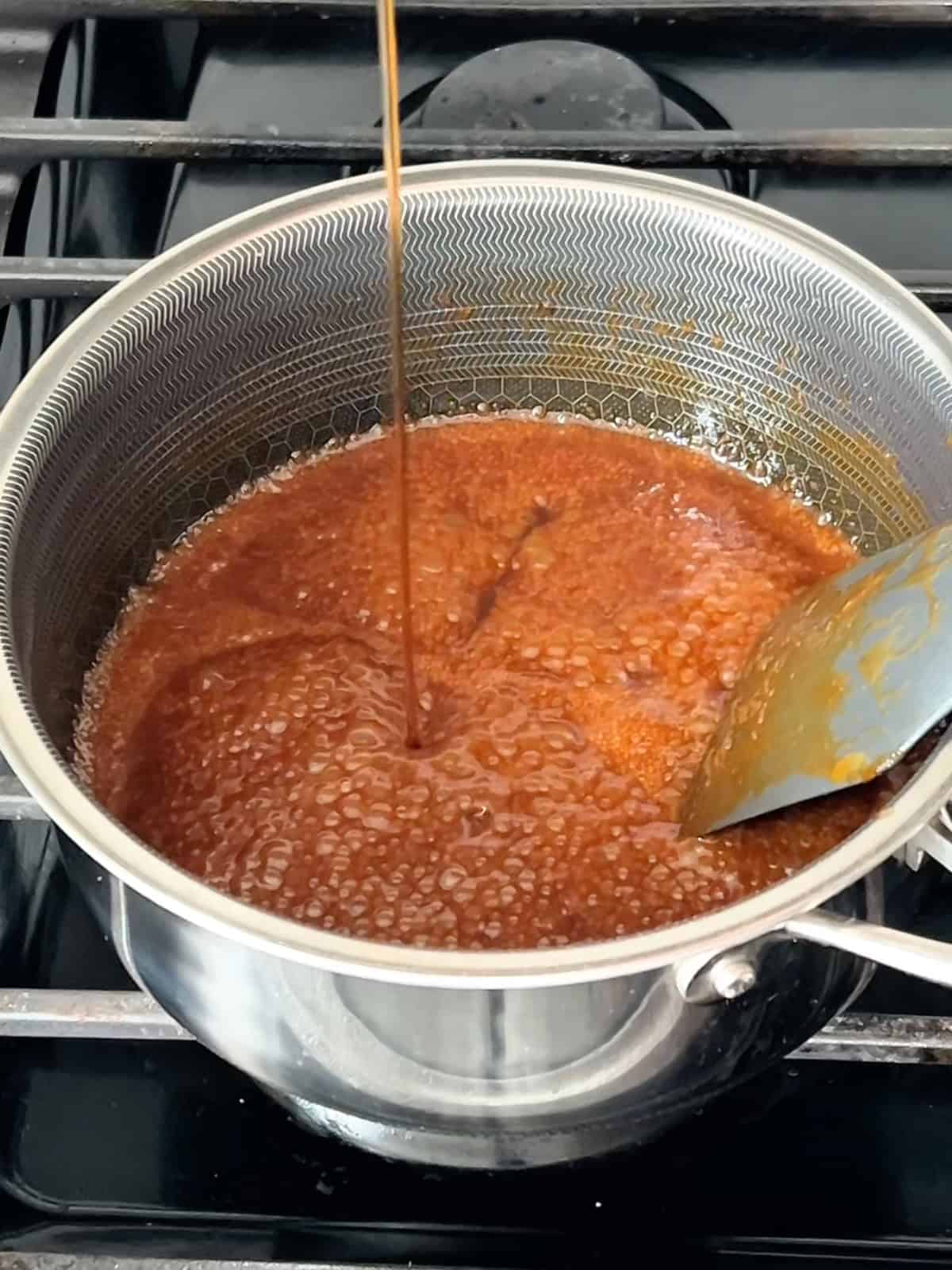 Adding fish sauce to the finished caramel sauce.