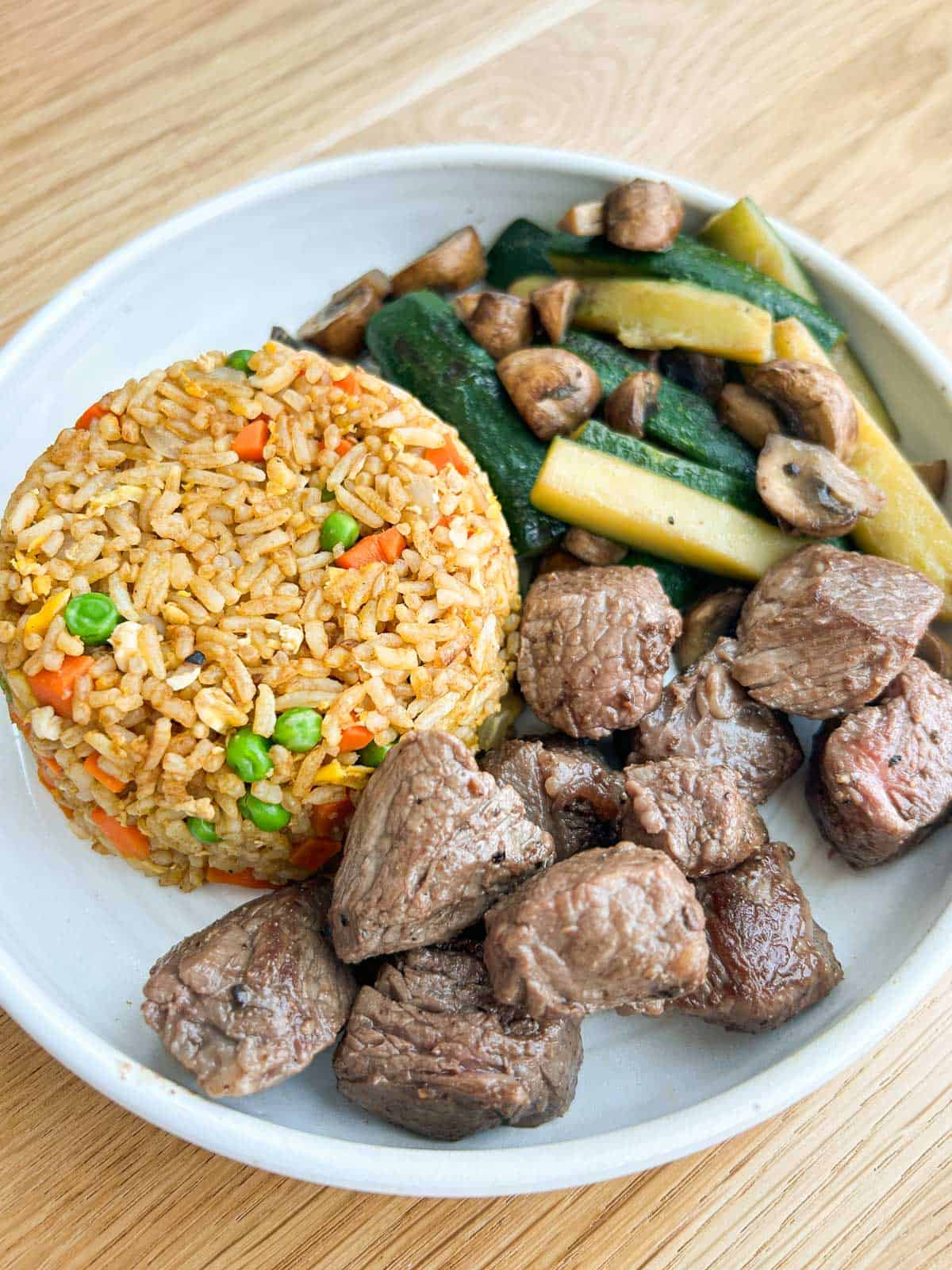 Steak, veggies, and fried rice in a bowl plate.