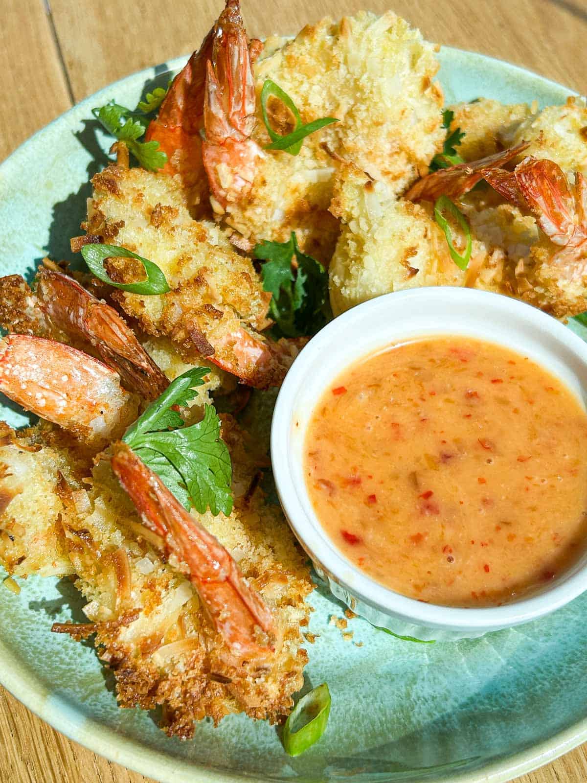 Angled close up shot of the plated coconut shrimp with bang bang sauce.