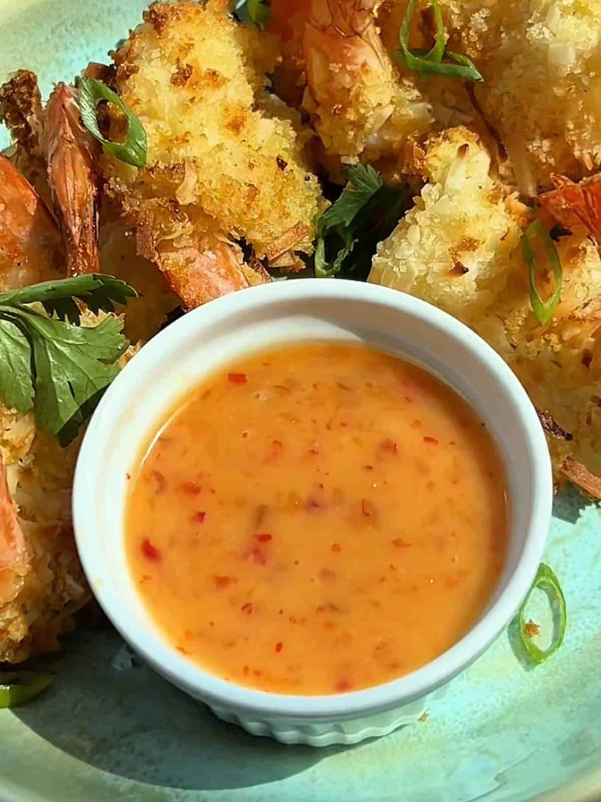 Close up shot of the bang bang sauce surrounded by coconut shrimp.
