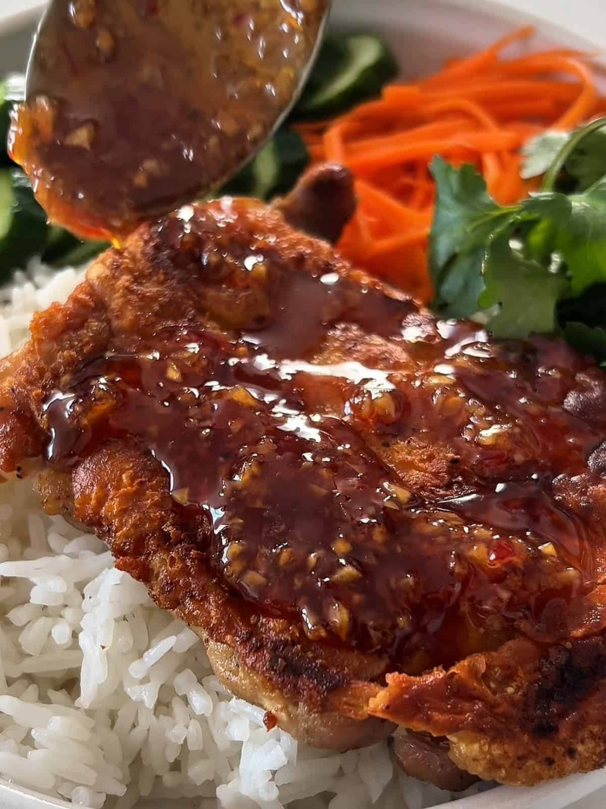 Fish sauce glaze drizzled over crispy chicken thighs on a bed of rice.