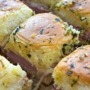 Close up side view of ham and cheese sliders on a cutting board.