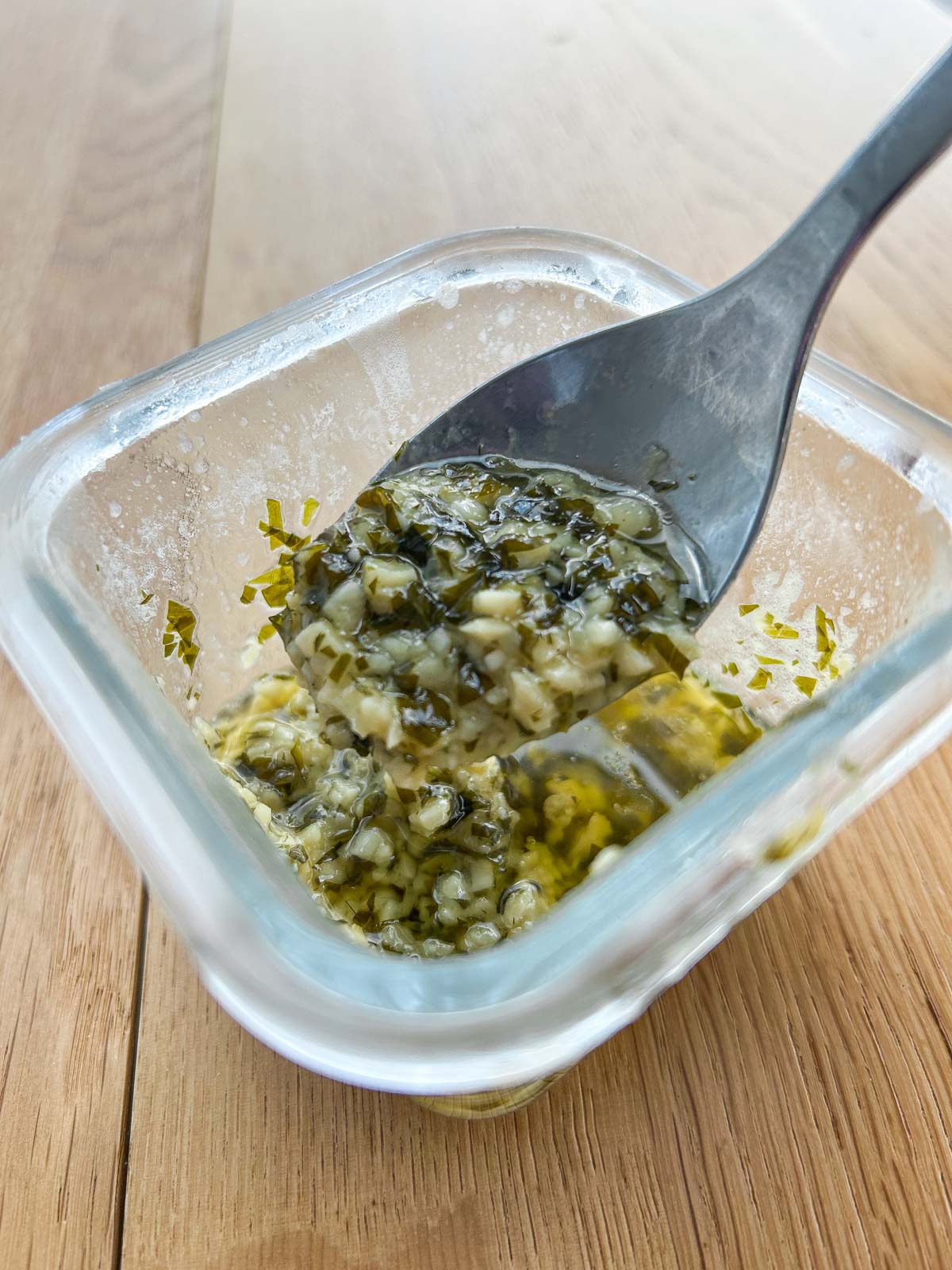 Melted garlic butter herb mixture in a container.