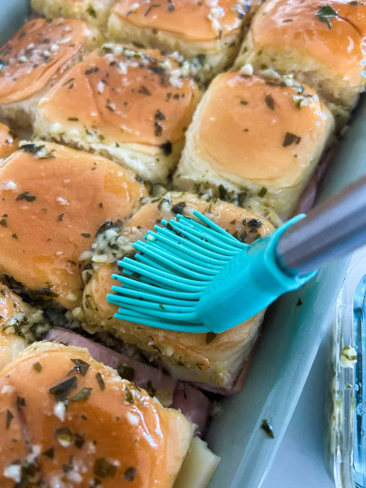 King's Hawaiian roll sliders in a baking dish with garlic butter brushed on top.