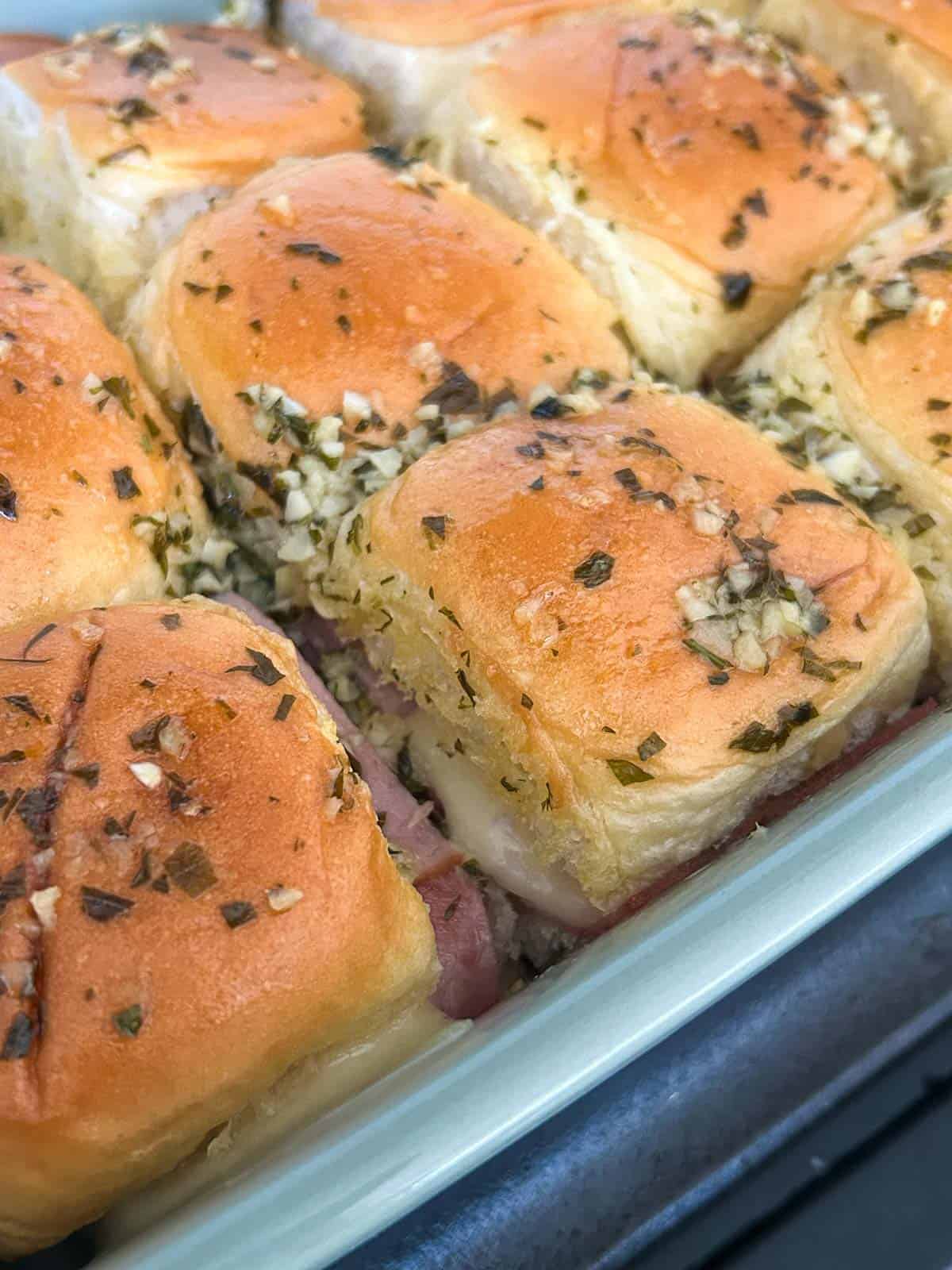 Side view of baked King's Hawaiian roll sliders in a baking dish with melted cheese.
