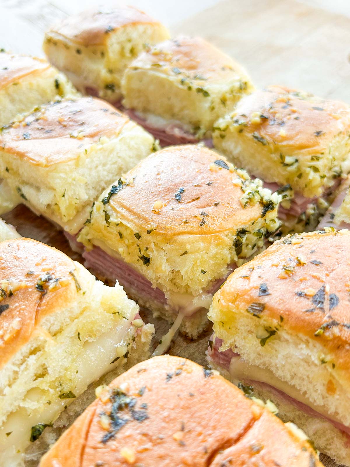 Side view of baked ham and cheese sliders with cheese pull.