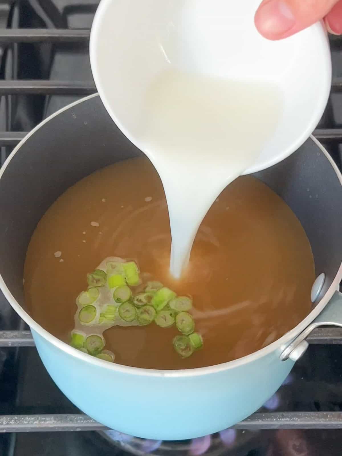Cornstarch slurry poured into a pot of broth.