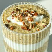 Close up 45 degree angle of pumpkin chia pudding topped with a dollop of greek yogurt and chopped pecans.