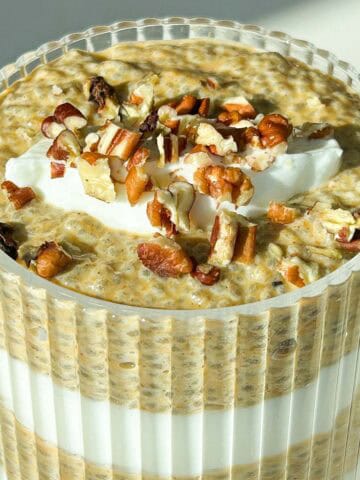 Close up 45 degree angle of pumpkin chia pudding topped with a dollop of greek yogurt and chopped pecans.