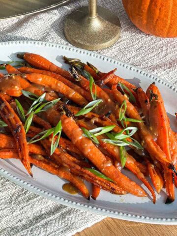 45 degree angle of roasted miso glazed carrots on plate on a table.