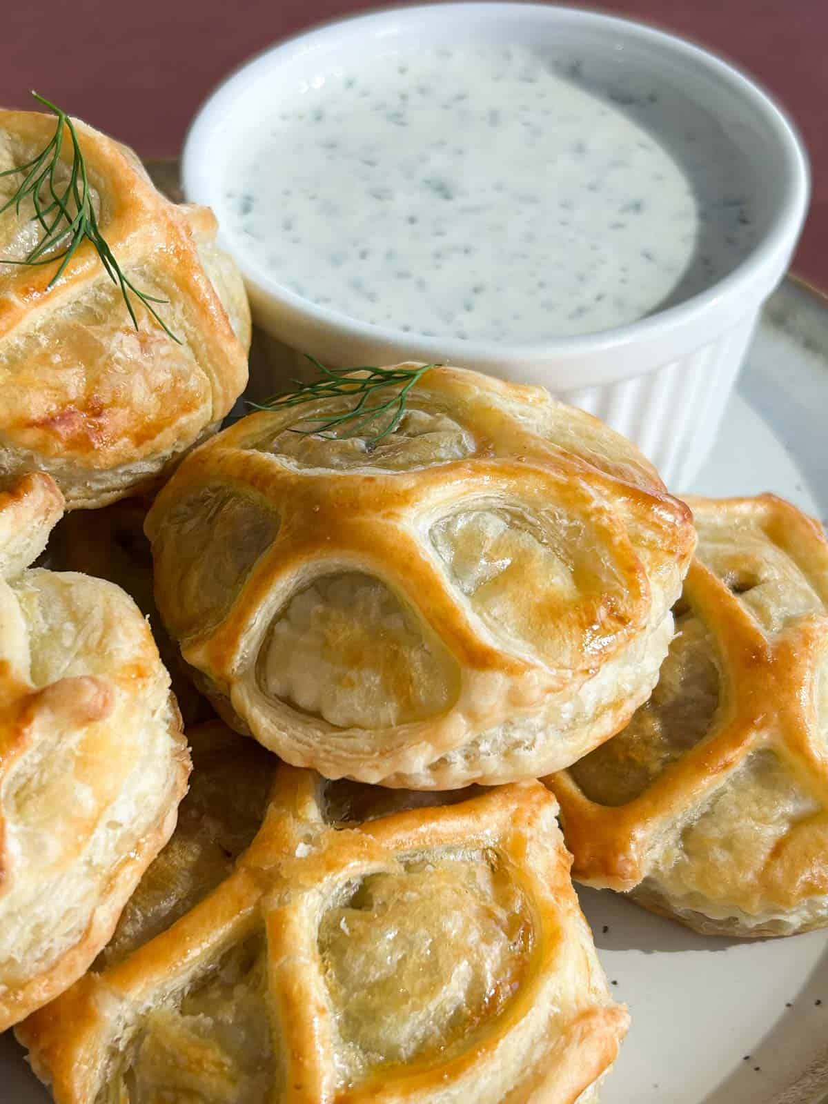 Close up shot of the finished salmon wellington pastries on a plate with dill dipping sauce.