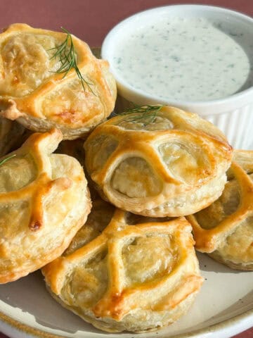 A plate of salmon wellington pastry bites with a creamy dill dipping sauce.