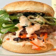 Close up shot of burger with sriracha mayo dripping down the burger.