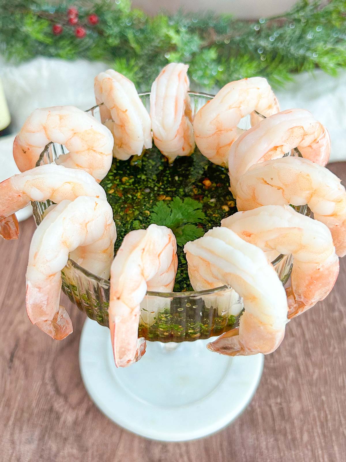 45 degree angled view of shrimp cocktail hanging on a coupe glass with Thai-style dipping sauce inside.