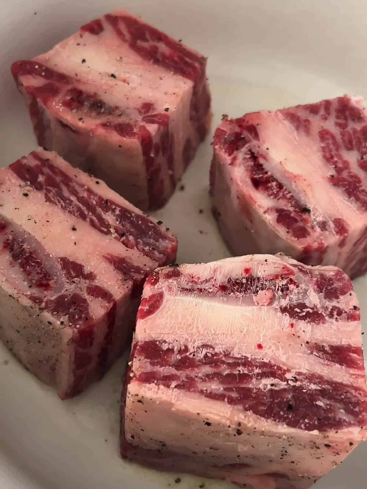 Bone in short ribs searing in a dutch oven.